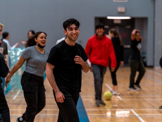 Group of young people smiling and walking inside a gymnasium.