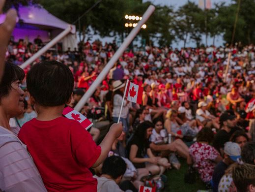 A kid waves a Canadian flag with a crowd in the background.