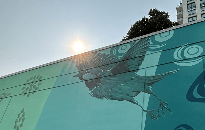 Sun peaking over the edge of a mural paining of of bird taking flight.